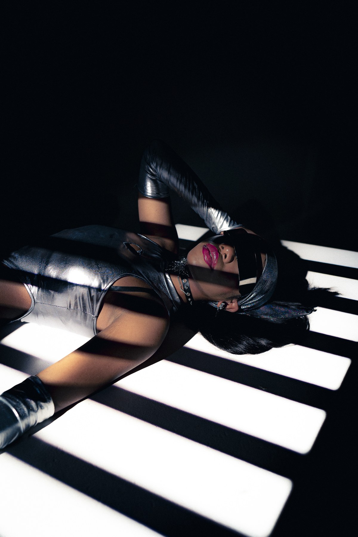 Portrait in silver clothing, crossed by bands of light and deep shadow.