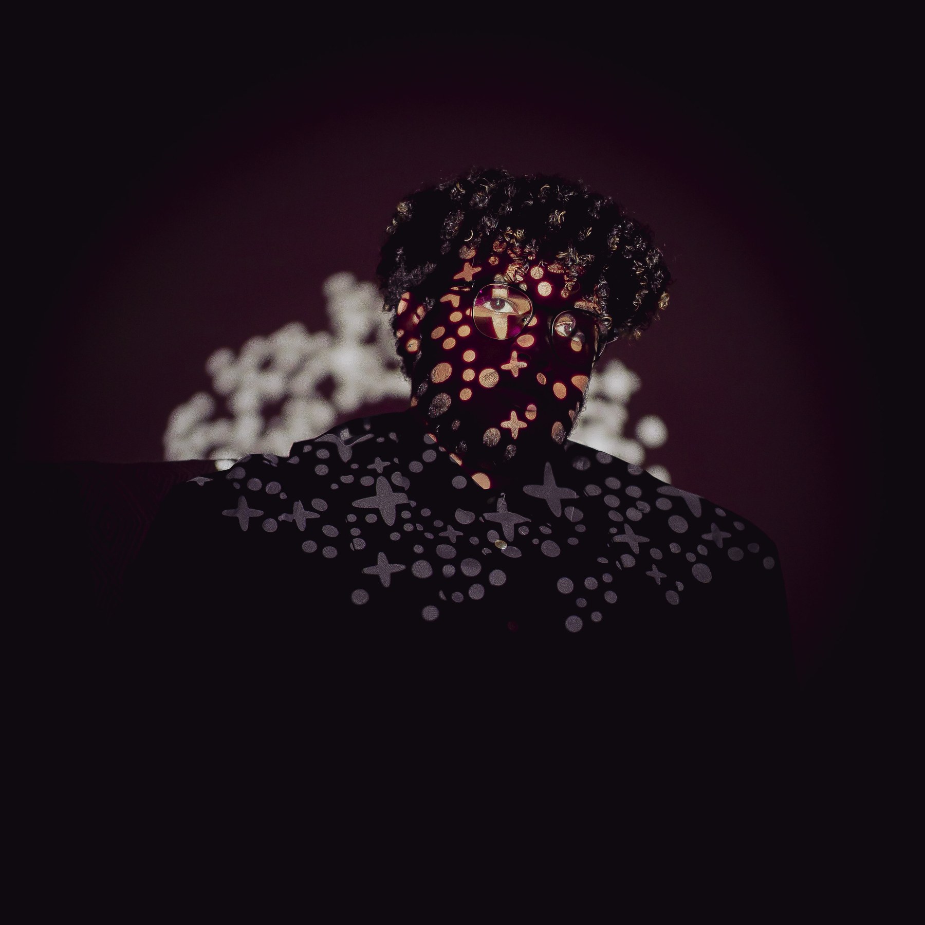 Portrait with bright shapes projected across the face against a dark background.